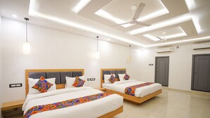 A hotel room with two beds, a ceiling fan, recessed lighting, and a tiled floor.