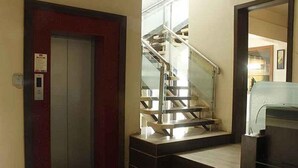 A red door with a security card reader, a metal staircase with glass railings, and a trash bin. - FabHotel Skylark Inn (Nashik)