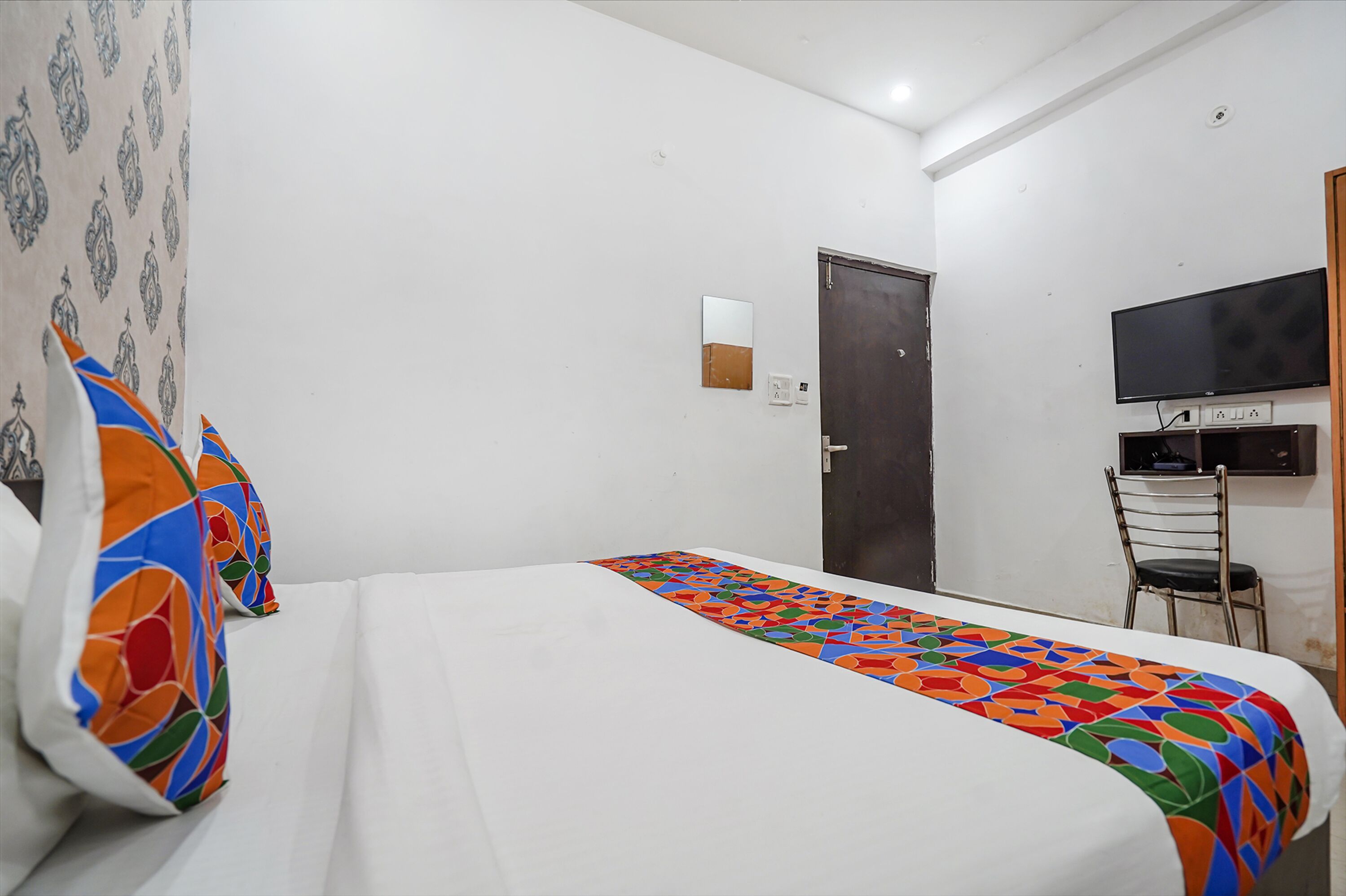 A hotel room with a bed, a TV, and a chair.