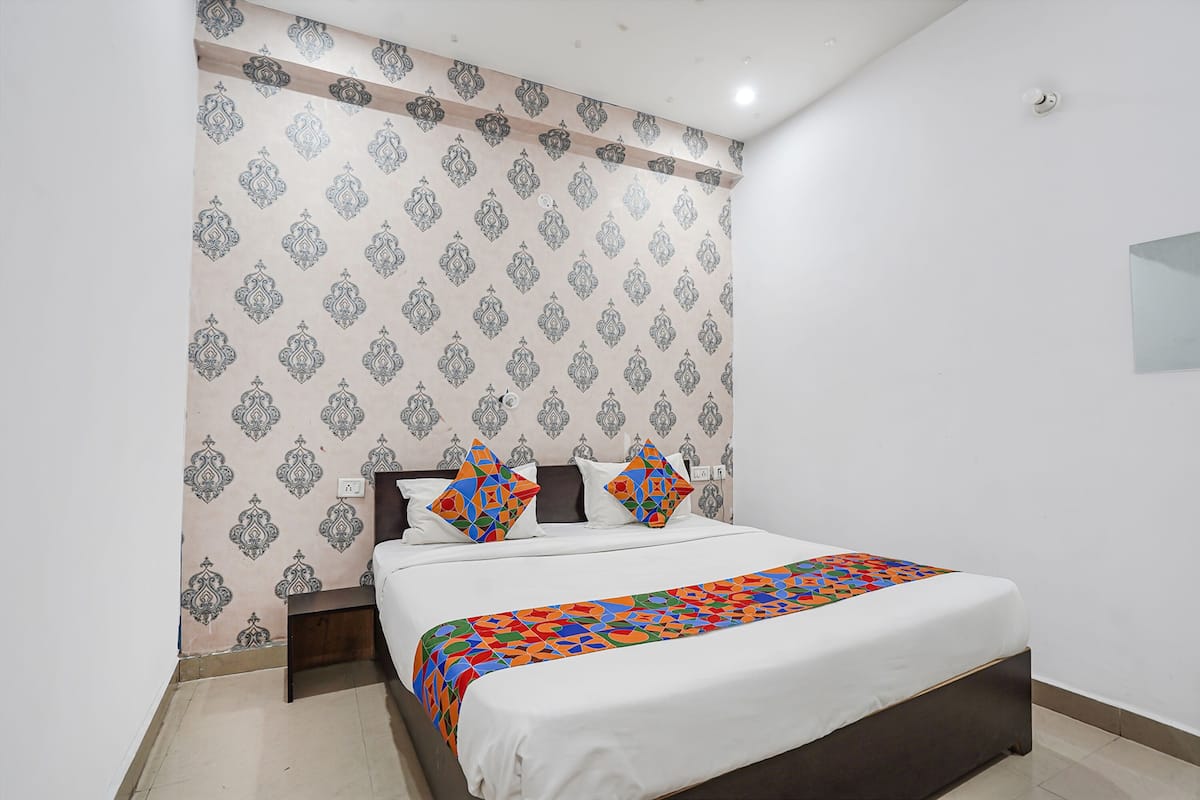 A bedroom with a bed, patterned wallpaper, and a colorful bedspread.
