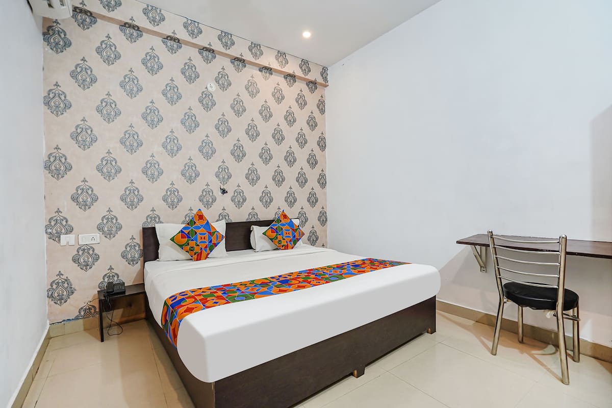 A neatly arranged bedroom with a bed, bedside table, and a desk with a chair.