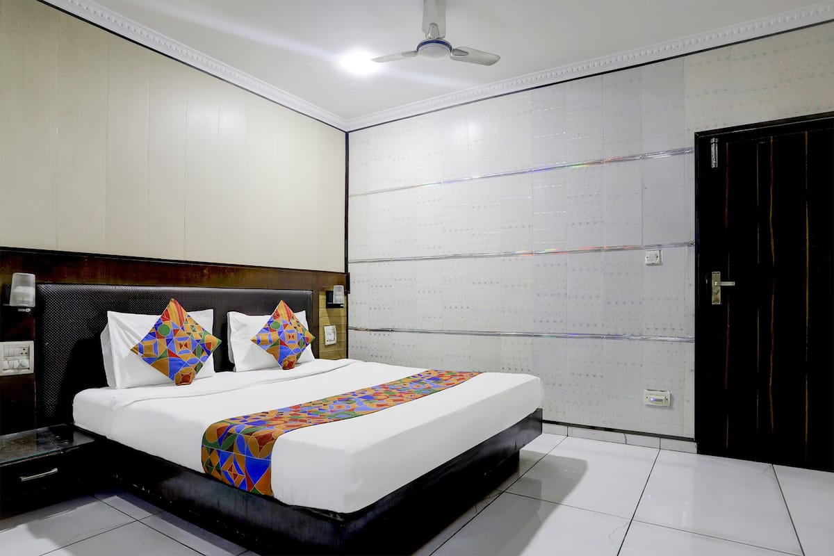 Una habitación de hotel con una cama grande, un ventilador de techo y una pared con diseño de cuadrícula.