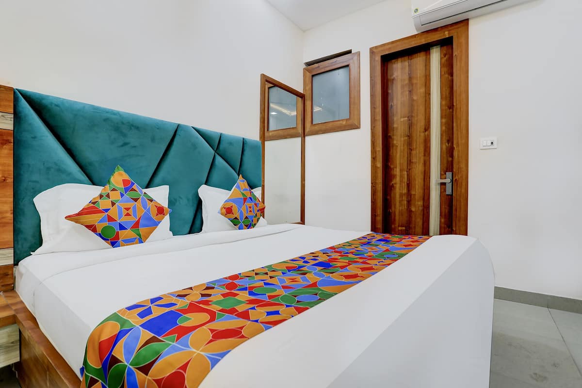 A neatly made bed with a colorful geometric-patterned bedspread and two pillows with a similar design.