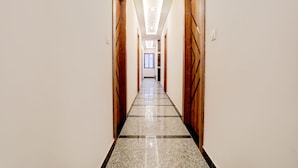 A long, narrow hallway with wooden doors on both sides and a tiled floor. - FabHotel SMR (Agra)