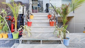 A set of outdoor stairs with potted plants on both sides, leading to a building entrance. - FabHotel SMR (Agra)