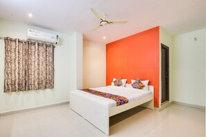 A bedroom with a bed, an air conditioner, a ceiling fan, and a window with curtains.