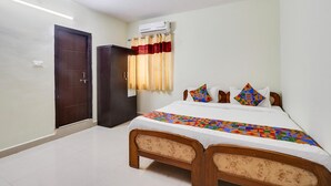 A bedroom with a bed, a ceiling fan, a door, and an air conditioning unit. - FabExpress Royal Prime Suits (Hyderabad)
