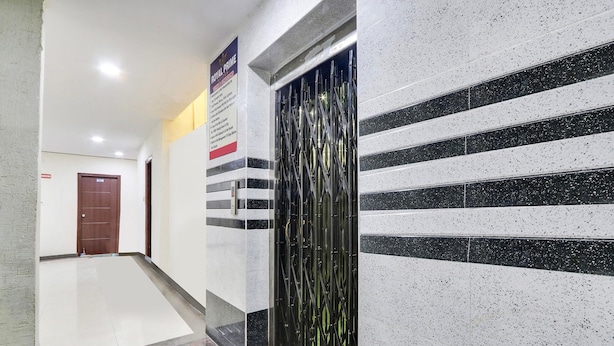A hallway with a polished floor, a metal gate, and a door in the background. - FabExpress Royal Prime Suits (Hyderabad)