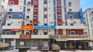 A multi-story building with a sign for AR Stay Inn, indicating it offers co-living and guest rooms. - FabExpress Royal Prime Suits (Hyderabad)