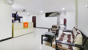 A hotel lobby with a reception desk, seating area, and a staircase leading to another floor. - FabExpress Royal Prime Suits (Hyderabad)