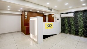 A reception desk with a 'fab hotels' sign, a reception area, and a wall with a green leafy design. - FabHotel Prime Simran (Rajkot)