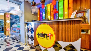 A restaurant with a checkered floor, a counter with a yellow sign, and colorful decorations. - FabHotel Naivara Boutique (Udaipur)