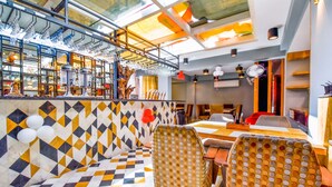 A restaurant with a checkered floor, patterned chairs, and a bar area with hanging glasses. - FabHotel Naivara Boutique (Udaipur)