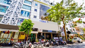 A building with a boutique hotel sign, multiple parked motorcycles, and a tree in the foreground. - FabHotel Naivara Boutique (Udaipur)