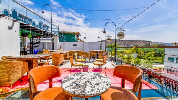 An outdoor patio with wicker furniture and a pool, overlooking a scenic landscape. - FabHotel Naivara Boutique (Udaipur)
