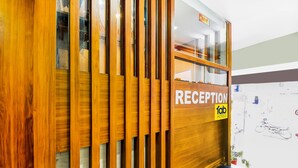 A reception area with a wooden reception desk and a glass partition. - FabHotel Naivara Boutique (Udaipur)