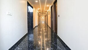 A modern, well-lit hallway with a reflective floor, leading to a door at the end. - FabHotel Embrace (New Delhi)
