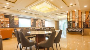 A modern dining area with a round table surrounded by chairs, a decorative wall, and a reflective floor. - FabHotel Embrace (New Delhi)