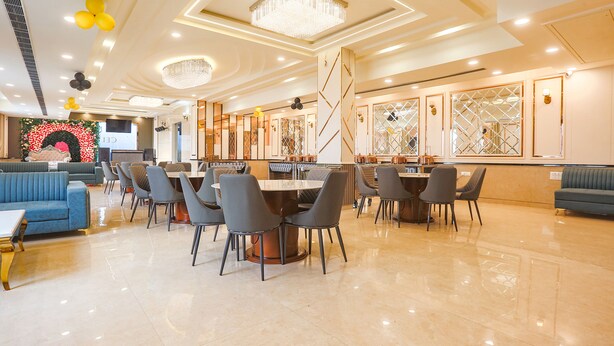 A spacious hotel lobby with a central round table surrounded by chairs, a blue sofa, and a chandelier. - FabHotel Embrace (New Delhi)