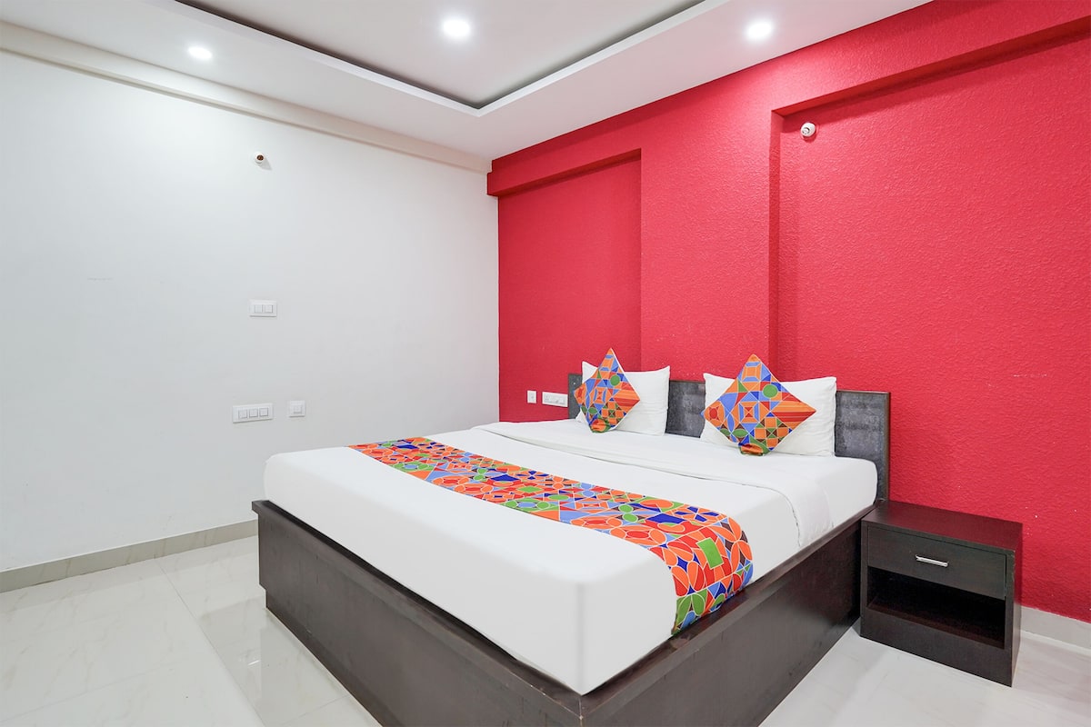 A modern bedroom with a large bed, a nightstand, and a red accent wall.
