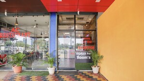 The entrance of a hotel with a reception desk, a contact phone, and potted plants.