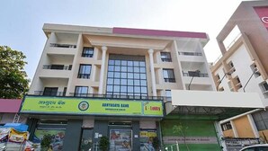 Un edificio de varios pisos con un amplio ventanal y un letrero del Banco Abhyudaya.