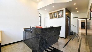Un mostrador de recepción con encimera de mármol negro, un pequeño objeto rojo encima y una obra de arte colgada en la pared.