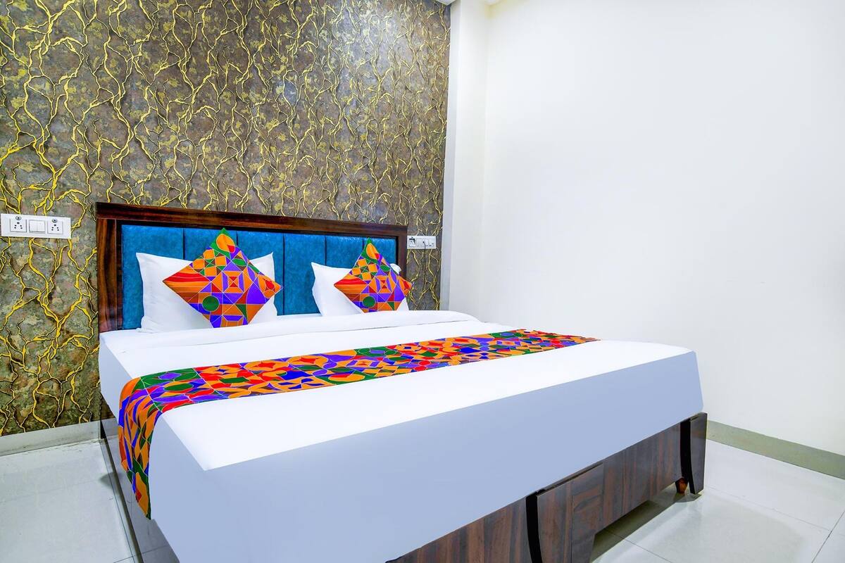 Una cama con una colcha de estampado geométrico, un cabecero de madera y dos almohadas con diseños parecidos.