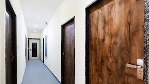 A hallway with wooden doors and a grey carpet. - FabHotel Ritik (Indore)