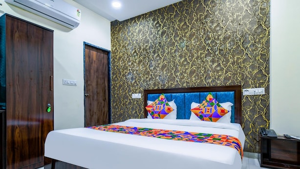 A hotel room with a bed, wooden wardrobe, and a wall with a crackle pattern. - FabHotel Ritik (Indore)
