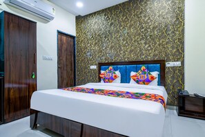 Quarto de hotel com cama, guarda-roupa de madeira e parede com padrão texturizado.