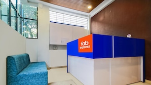 A reception area with a blue and white desk labeled 'fab express', a blue sofa, and a window with blinds. - FabHotel Ritik (Indore)