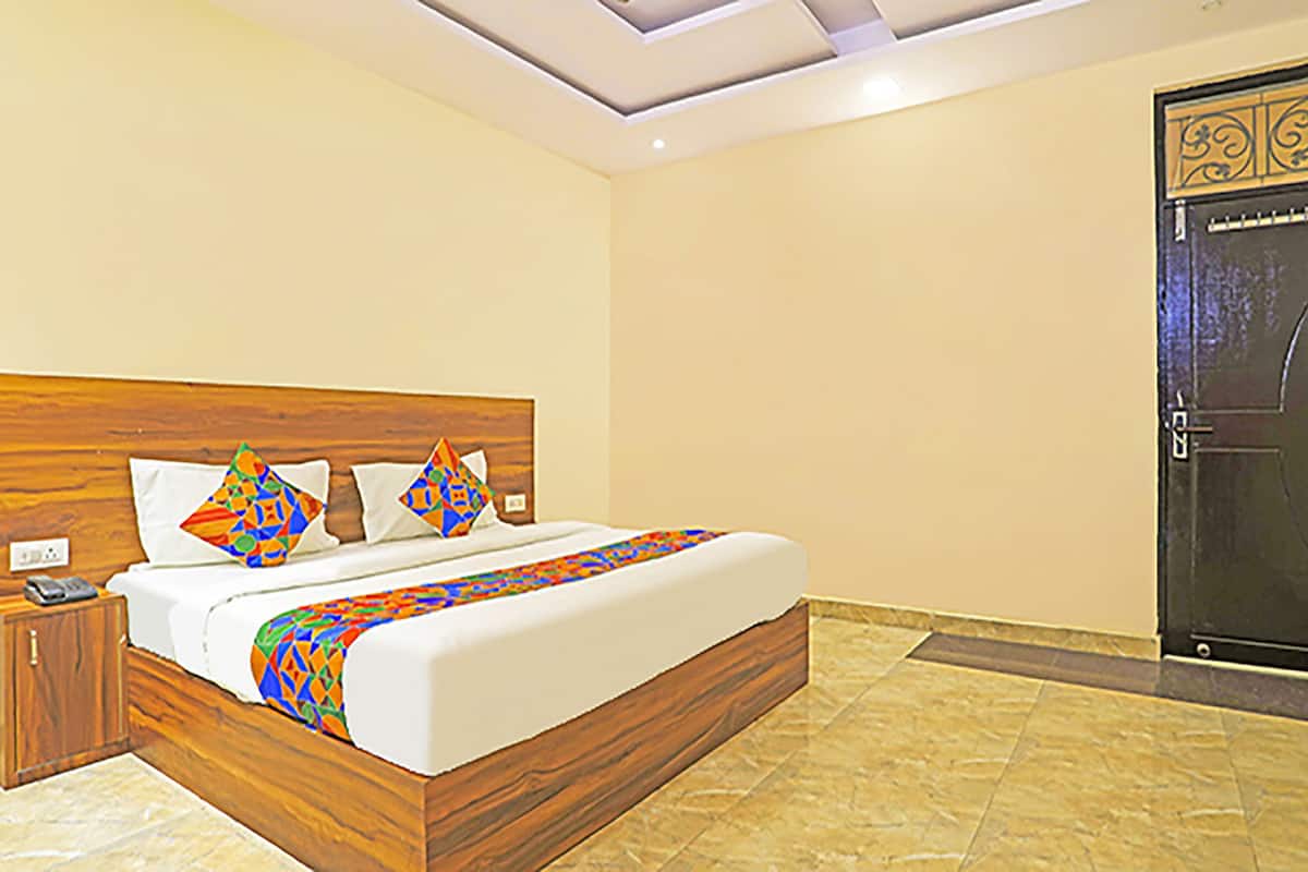 Un dormitorio con cabecera de madera, una cama con almohadas de colores, una mesita de noche con un teléfono y una puerta con paneles decorativos.