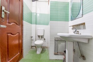 Uma casa de banho com sanita, lavatório e chuveiro.