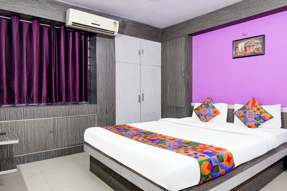Quarto moderno com cama grande, guarda-roupa e parede de destaque roxa.