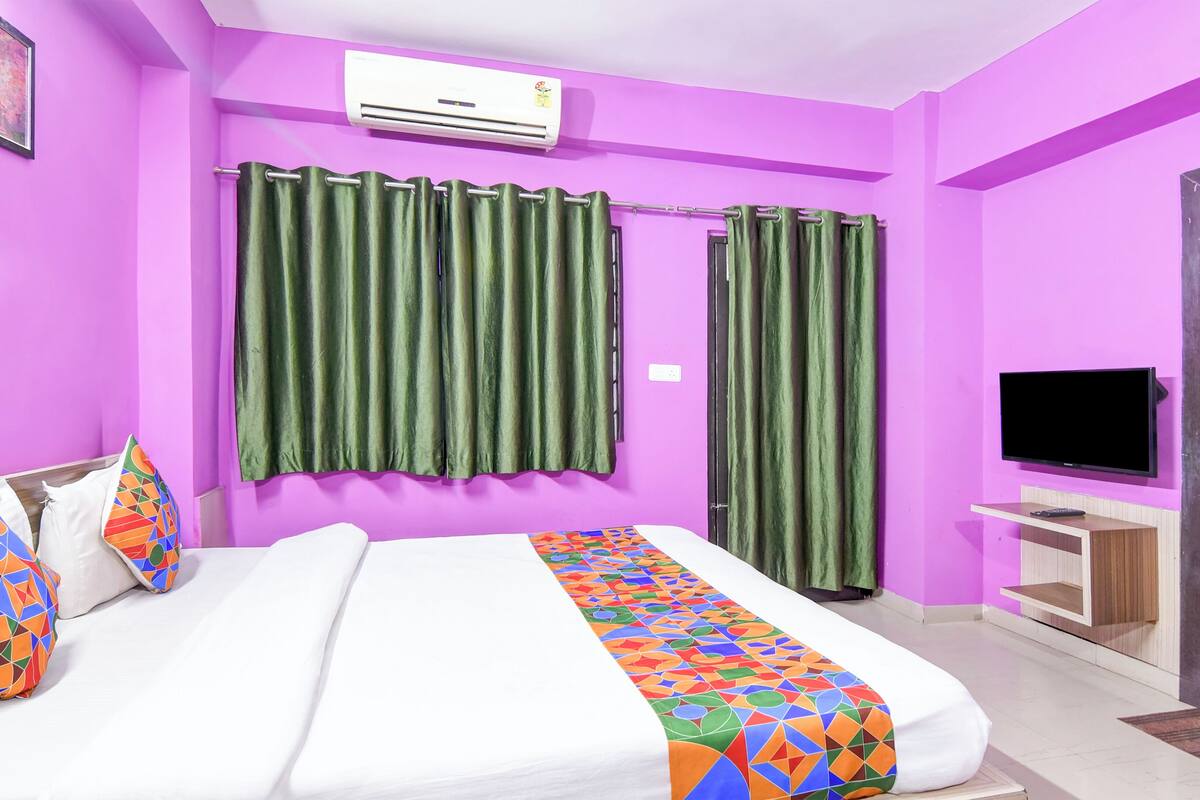 Um quarto com uma cama, uma televisão e uma porta.