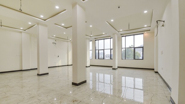 Una habitación de hotel amplia con ventanas grandes, piso de mármol y un diseño moderno en el techo.