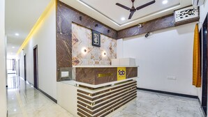 Zona de recepción de un hotel con un mostrador de mármol, un ventilador de techo y un cuadro en la pared.