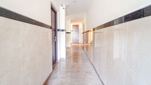 A long, narrow hallway with marble walls and a polished floor, leading to a door at the end. - FabHotel HR Residency (Coimbatore)