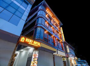 Um edifício de vários andares com uma placa chamativa para o Ruby Hotel e Restaurante.