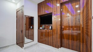 A room with a wooden wardrobe, a flat-screen TV, and a mirror. - FabExpress Miss Too (Noida)