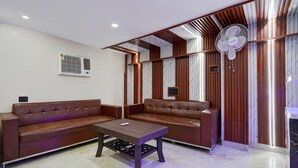 A modern living room with leather sofas, a wooden coffee table, and a ceiling fan. - FabExpress Miss Too (Noida)