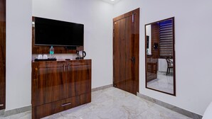 A room with a wooden wardrobe, a flat-screen TV mounted on the wall, and a mirror reflecting part of the room. - FabExpress Miss Too (Noida)