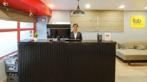 A reception desk with a modern design, a flat-screen TV, and a sign for Fab Hotels.