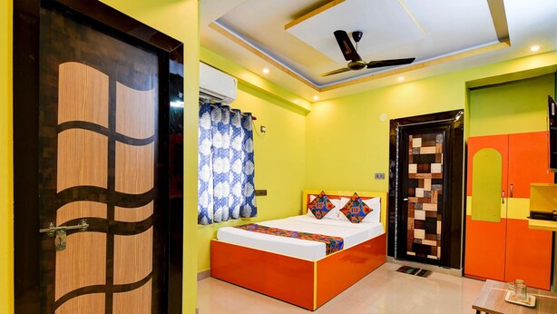 A bedroom with a bed, a ceiling fan, and a door with a geometric pattern. - FabHotel Dreamz Heaven (Barasat)