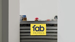 A reception desk with a 'fab hotels' sign, a calendar, a vase with pink flowers, and a fan. - FabHotel Dreamz Heaven (Barasat)