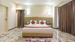 Een hotelkamer met een groot bed, een nachtkastje, een telefoon en een plafondventilator.