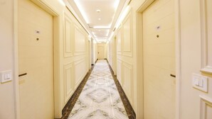 Een hotelgangen met crèmekleurige deuren, genummerd 207 en 205, en een vloer met een marmerpatroon.