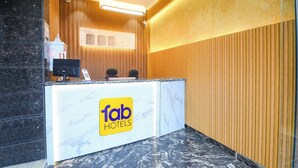 Een hotel receptie met een marmeren balie, houten lambrisering en een moderne kroonluchter.