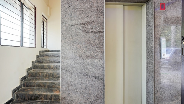 A staircase with a handrail and a door leading to an elevator. - FabHotel Leo Grand (Anekal)